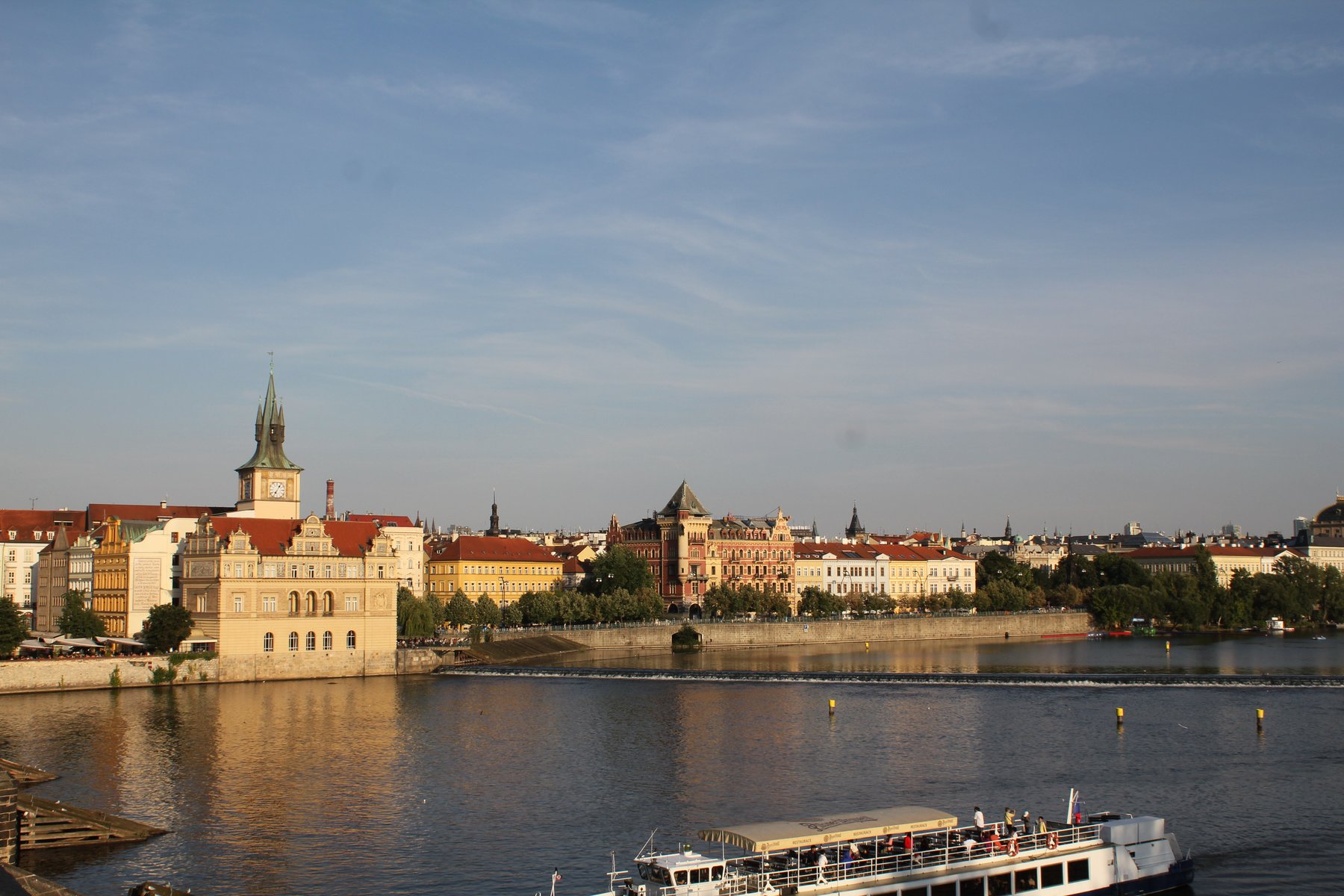 Prague riverside at golden hour, with boat